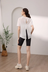 Vue arrière du haut de yoga blanc fendu et du short de cyclisme noir pour femmes