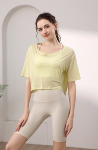 Detail eines gelben Mesh-Yoga-Oberteils und beigen High-Waist-Sportshorts an einem Model