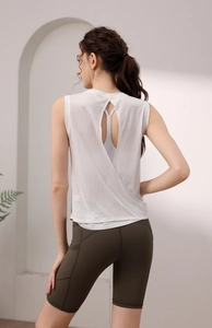 Detail of cross-back open design on white yoga tank top with olive green gym shorts