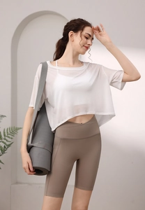 Detail eines atmungsaktiven weißen Netz-T-Shirts und khakifarbener Yoga-Shorts für Fitness