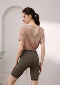 Détail d'un t-shirt rose-brun ample avec dos ouvert et soutien-gorge de sport blanc croisé
