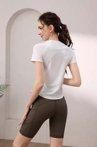 Dettaglio del top da yoga bianco dry-fit con cuciture posteriori curve e pantaloncini a vita alta