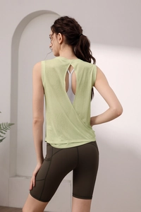 Detail of light green open back yoga top with white sports bra and olive green biker shorts
