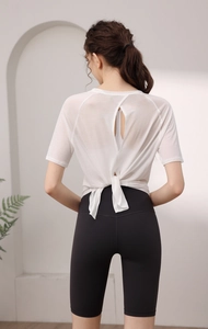 Détail du dos en maille respirante avec un nœud sur le haut de yoga blanc et le short noir
