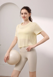 Detail von hellgelbem Tencel-Crop-Top und beigen High-Waist-Yoga-Shorts am Model