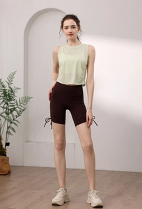 Detail view of light green drawstring yoga tank top and brown high waist gym shorts