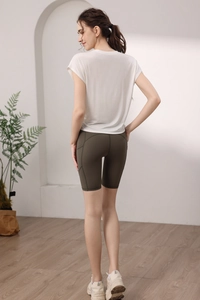 Λεπτομερής πίσω όψη λευκού yoga t-shirt και λαδί κολάν ποδηλασίας με πρακτική πλαϊνή τσέπη