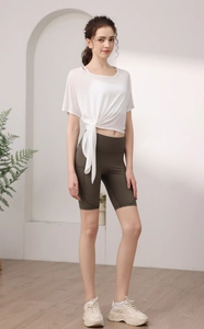 Détail du haut de yoga blanc en tencel avec lien latéral et short de sport vert taille haute