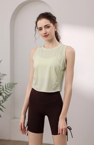 Detail of light green yoga tank top with side pleats and brown high-waisted gym shorts