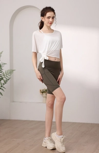 Détail du t-shirt blanc noué translucide et du short de yoga cycliste vert olive