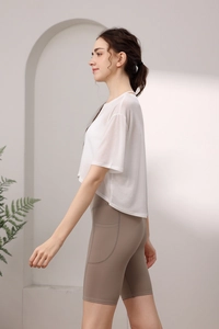 Detail von weißem Mesh-Sportoberteil und braunen Yoga-Shorts mit hoher Taille und Taschen