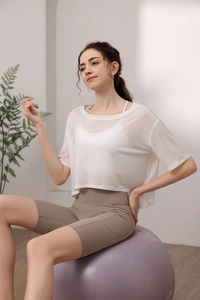 Detail eines lockeren weißen Mesh-Yoga-T-Shirts und taupefarbenen Shorts auf einem Ball