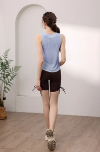 Vista posteriore di un top sportivo azzurro con pantaloncini da yoga marroni con lacci