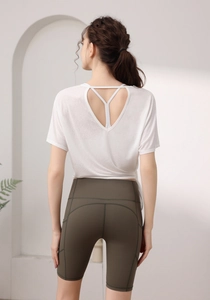 Détail du haut de sport blanc en tencel dos nu et short de cyclisme vert à taille haute