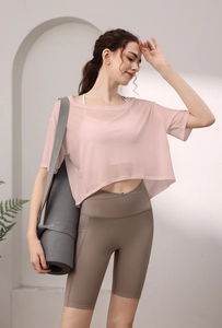 Detail eines rosa Netz-Sportoberteils mit weißem Sport-BH und dunkelbraunen Shorts