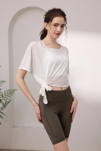 Détail du t-shirt de yoga blanc noué et du short cycliste olive pour le fitness