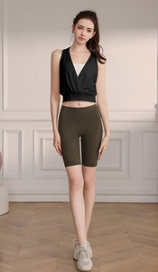 Detail of female athlete wearing deep V-neck yoga vest and green high-waisted gym shorts
