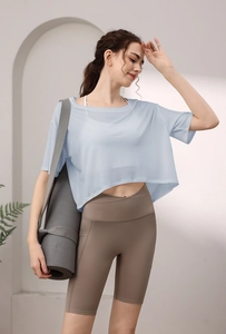 Hellblaues kurzes Sporttop und khaki High-Waist Gym-Shorts an einem Fitnessmodell