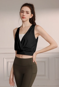 Detail of a chic black V-neck nylon jacquard yoga vest layered with a white sports bra