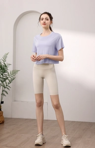 Detailansicht eines lila Yoga-Oberteils und beiger Radlerhose mit hoher Taille