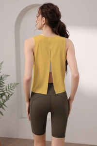 Dettaglio del top giallo con spacco sulla schiena e pantaloncini sportivi verde oliva