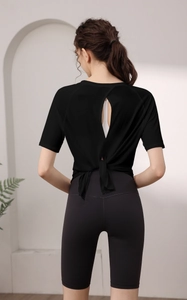 Détail du haut de yoga noir dos ouvert à nœud et leggings de sport gris à taille haute