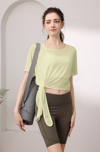 Détail du haut de yoga vert clair avec nœud latéral et short cycliste sur tapis