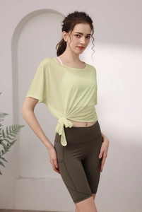 Détail du haut de yoga vert clair avec nœud latéral et leggings avec poches fonctionnelles