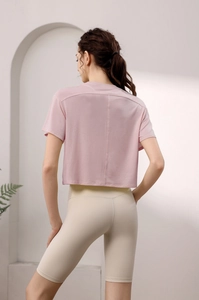 Rückansicht von lockerem rosa Sport-Crop-Top und beigen High-Waist Yoga-Shorts für Damen