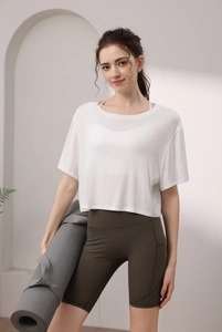 Détail d'un haut de yoga en modal avec short vert et un tapis de yoga gris