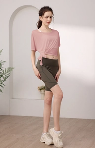 Détail du haut de yoga en maille rose avec nœud latéral et short de fitness taille haute vert
