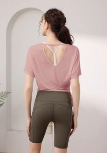 Vue détaillée du dos d'un haut de yoga rose avec découpe en cœur et d'un short de sport vert