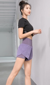 Vue latérale du short de sport violet taille haute et t-shirt noir en décor industriel