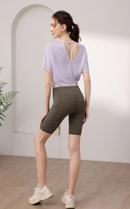 Détail du dos croisé d'un t-shirt de yoga mauve avec un short de cyclisme vert