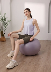 Dettaglio canotta yoga lavanda e pantaloncini da ciclista verdi su palla da ginnastica