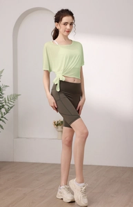 Détail du haut de yoga vert clair avec nœud latéral et short de cyclisme marron avec poche