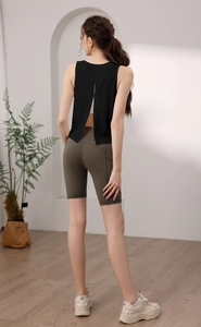 Vista posteriore del gilet sportivo nero con apertura sul retro e pantaloncini da yoga verdi