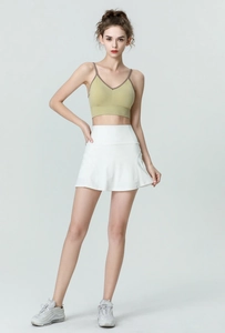 Détail de la jupe de tennis blanche taille haute et de la brassière de sport verte pour femme