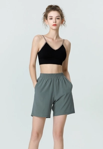 Detail of high-waist grey-green yoga shorts with side pockets and a black sports bra