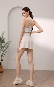 Close-up of high-waist pleated tennis skirt and white Y-back sports bra with cross straps
