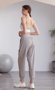 Dettaglio dei pantaloni sportivi grigio chiaro a vita alta con tasche laterali