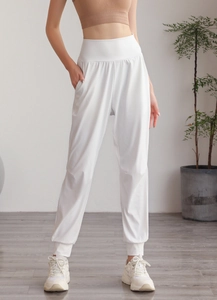 Dettaglio dei pantaloni yoga bianchi a vita alta con polsini elastici e tasche laterali