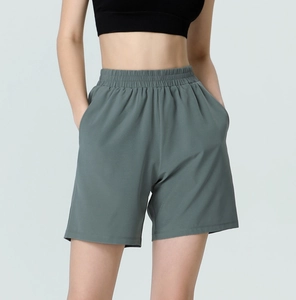 Detail of high-waisted gray-green sports shorts featuring elastic waistband and side pockets