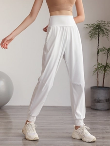 Dettaglio dei pantaloni sportivi bianchi a vita alta con fascia larga e polsini a coste