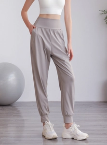 Dettaglio dei pantaloni sportivi taupe a vita alta con tasche laterali e polsini a coste