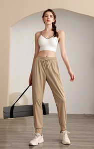 Nylon high-waisted loose joggers and white sports bra on a model in a minimalist room