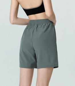 Back view of high waisted loose fitness shorts in dark grey green with elastic waist