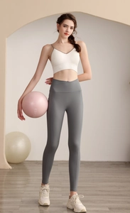 Detail van de grijze yoga broek met hoge taille en witte sportbeha op fitnessmodel