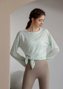 Détail du haut de yoga vert clair semi-transparent avec nœud latéral et legging de sport