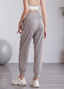 Dettaglio dei pantaloni sportivi kaki a vita alta con effetto snellente e polsini elastici